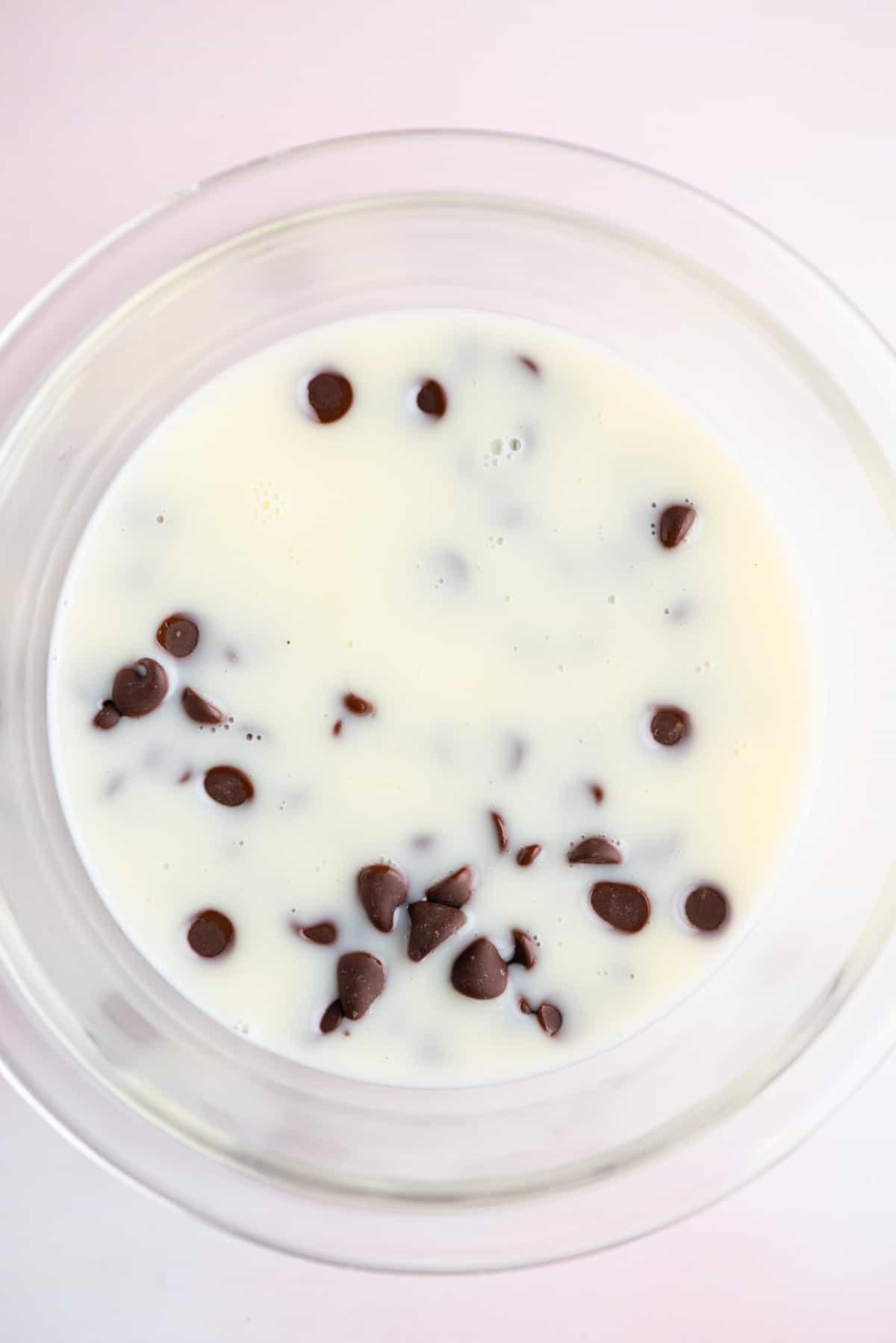 **Salsa Calda al Cioccolato Fondente** 9 Una miscela di panna fresca e zucchero in una ciotola di vetro con gocce di cioccolato
