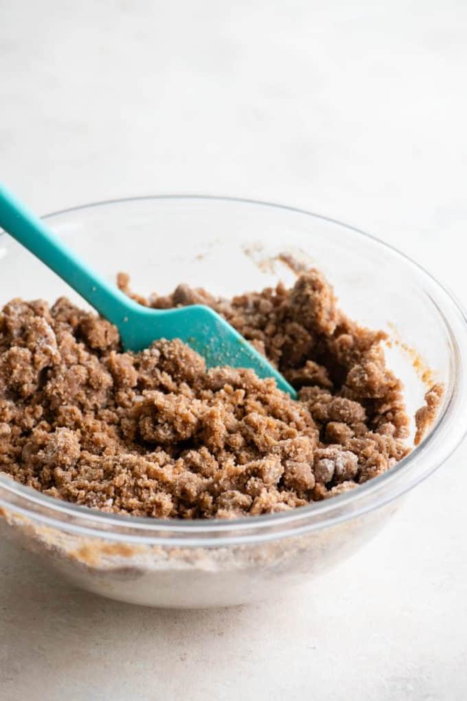 Ricetta Torta Umida al Caffè 9 Topping di crumble per torta al caffè in una ciotola di vetro trasparente con una spatola verde acqua al suo interno