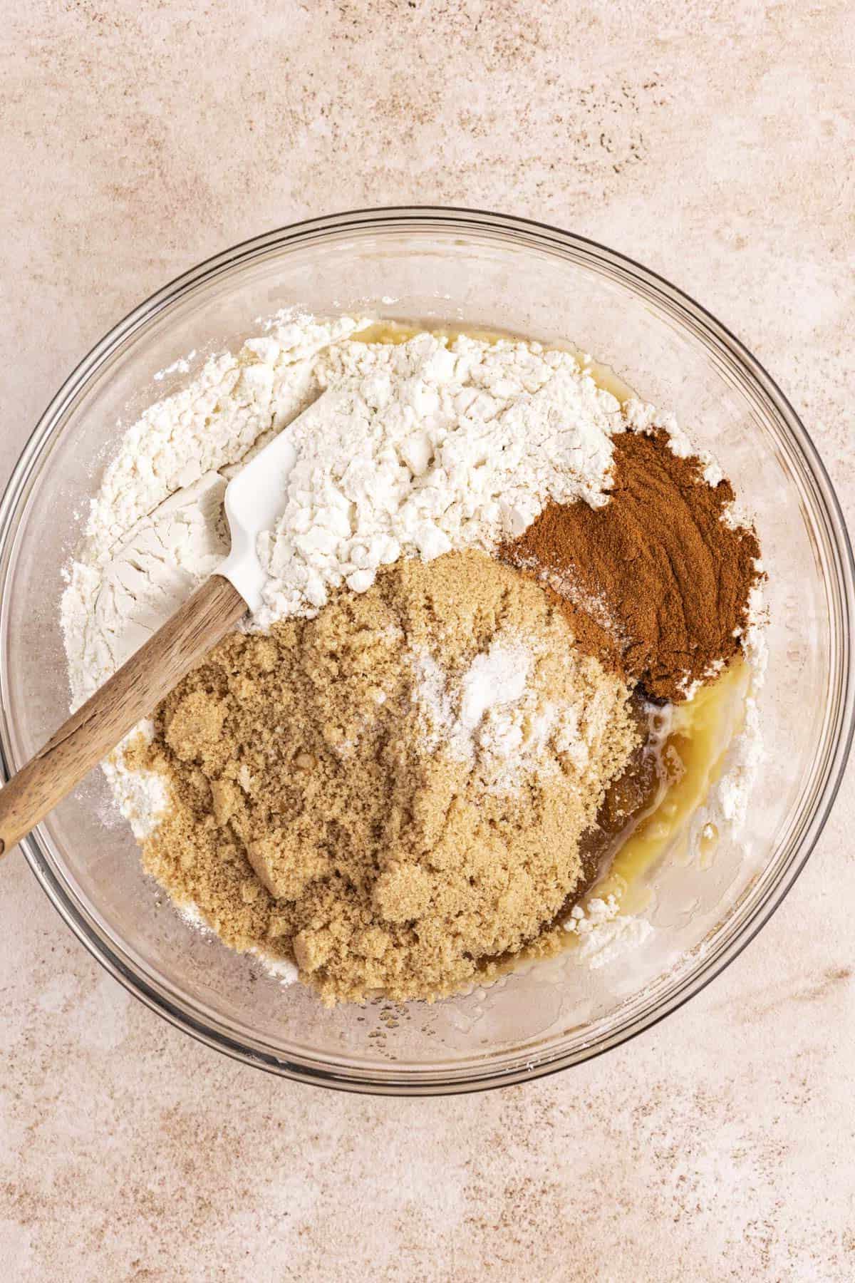 Migliore Ricetta per Budino di French Toast 9 Ingredienti per la casseruola di French Toast in una ciotola di vetro trasparente con una miscela di farina, cannella e zucchero di canna sopra, non ancora mescolati.