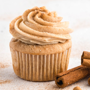 **Glassa al formaggio cremoso alla cannella** 9 Glaseado de queso crema con canela en un cupcake con palitos de canela al lado