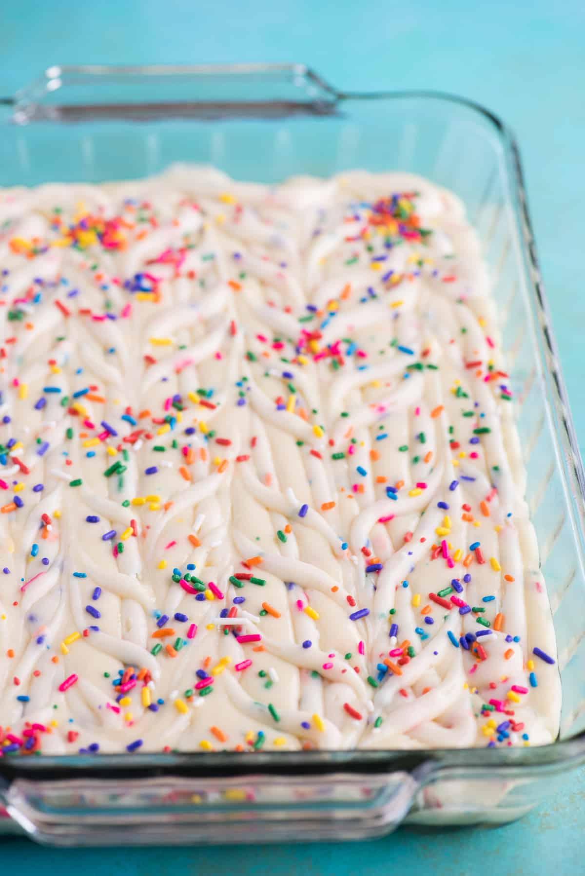 Questa torta terremoto funfetti è un mix per torta bianca arricchito con zuccherini e gocce di cioccolato funfetti. Lo strato di glassa al formaggio cremoso si fonde nella torta creando crepe e fessure in superficie. #earthquakecake #funfetticake #cake Impasto per torta terremoto funfetti in teglia di vetro 9x13 pollici