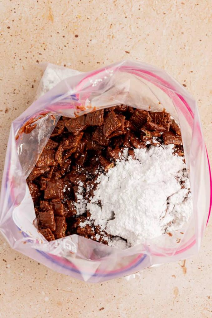 Cereali chex ricoperti di cioccolato in una grande busta con chiusura a zip con sopra un mucchio di zucchero a velo