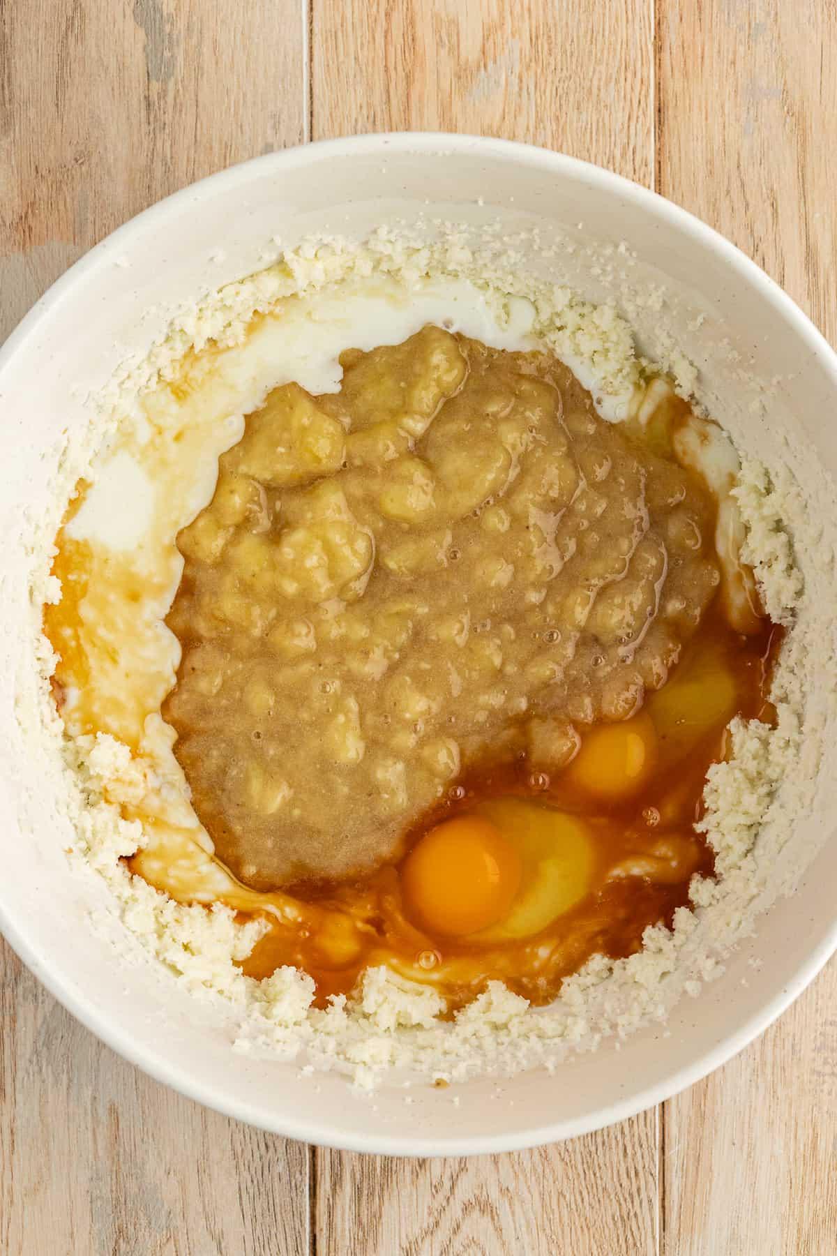 Ricetta Facile Torta alla Banana 10 Una ciotola bianca con una miscela di burro e zucchero, banane schiacciate, uova, latticello ed estratto di vaniglia non ancora mescolati