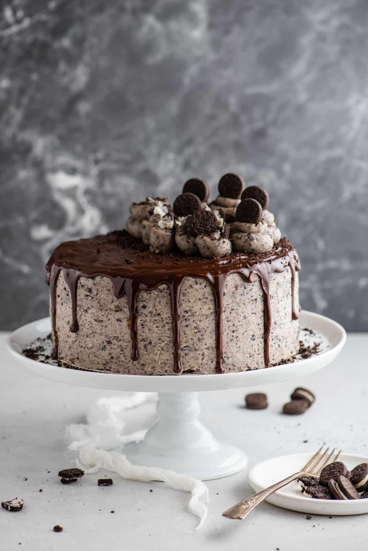 Questa torta Oreo fatta in casa è umida, ricca di sapore cookies-and-cream ed è più facile da fare di quanto tu possa pensare. Una torta a strati in stile pasticceria, fatta in casa! Torta Oreo intera su alzata per torte