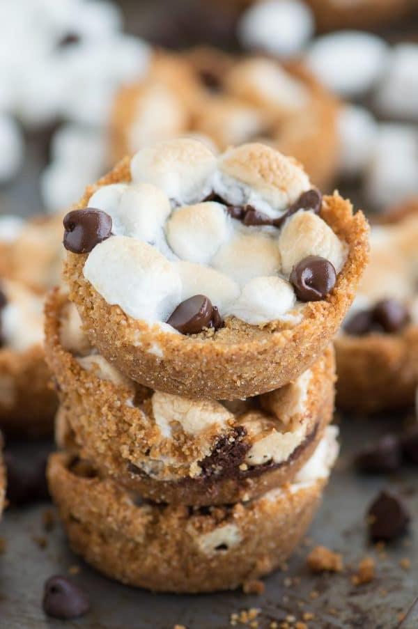 Tazze S'mores al Forno con 5 ingredienti! Preparale in uno stampo per muffin standard. Un incrocio tra biscotti s'mores e cupcake s'mores! Deliziose Tazze S'mores da Forno preparate con gocce di cioccolato e marshmallow.