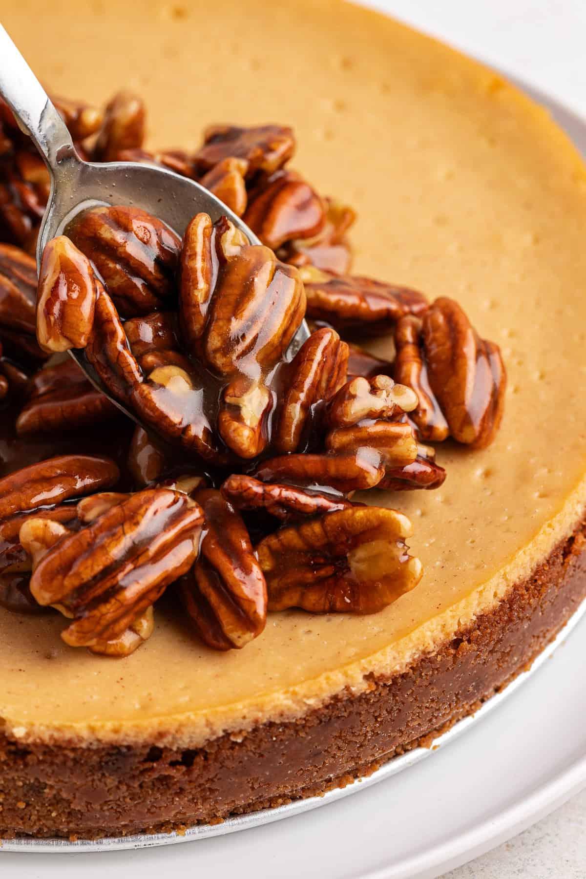 La Migliore Ricetta per Cheesecake alla Torta Pecan 14 Ripieno di noci pecan versato a cucchiaiate sulla cheesecake