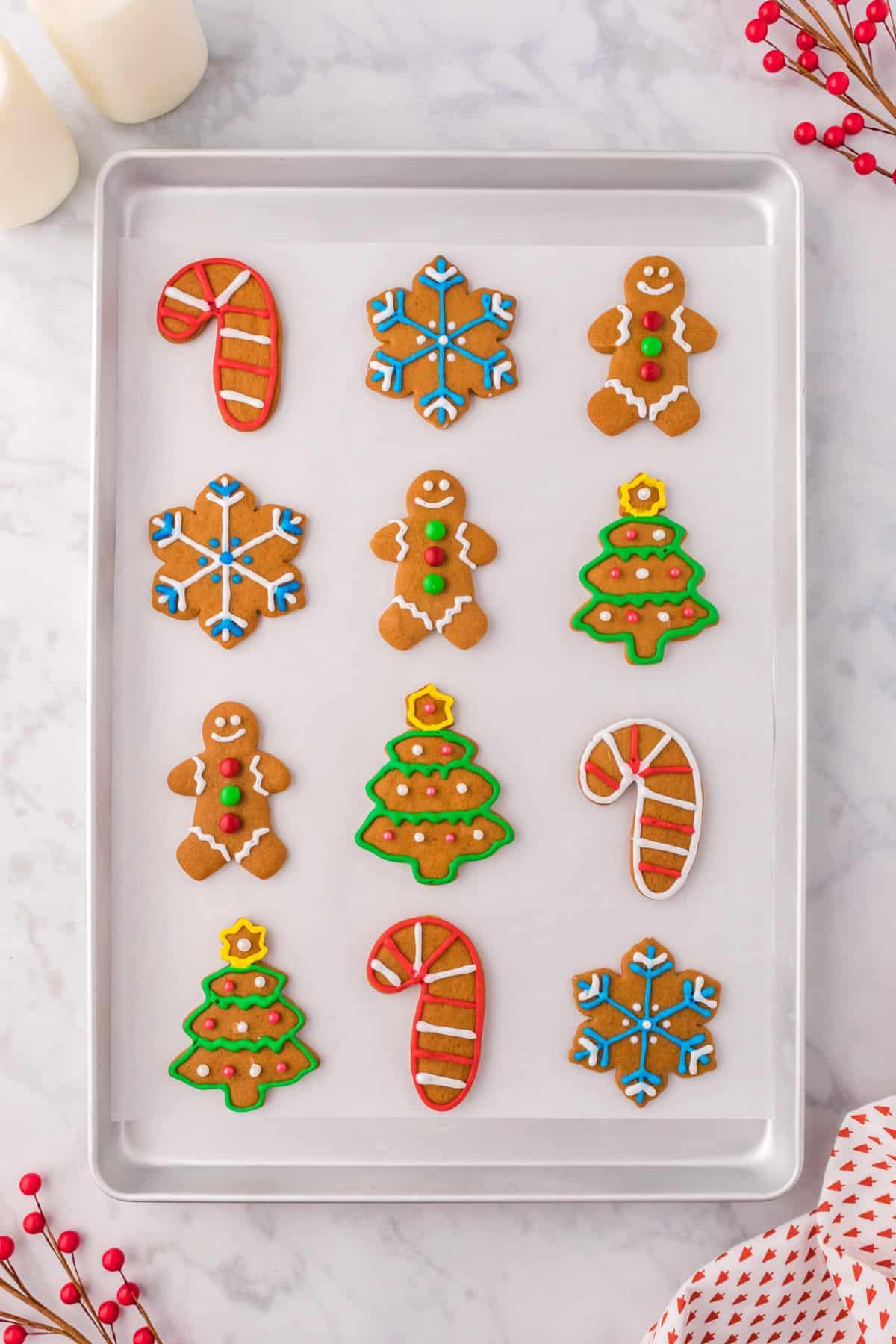 Glassa Reale senza Polvere di Meringa 16 un assortimento di biscotti di pan di zenzero decorati con ghiaccia reale allineati in file su una teglia da forno rivestita di carta forno