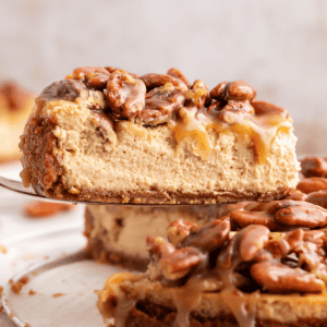 La Migliore Ricetta per Cheesecake alla Torta Pecan 18 Vista laterale di una fetta di cheesecake alle noci pecan sollevata dal resto della cheesecake