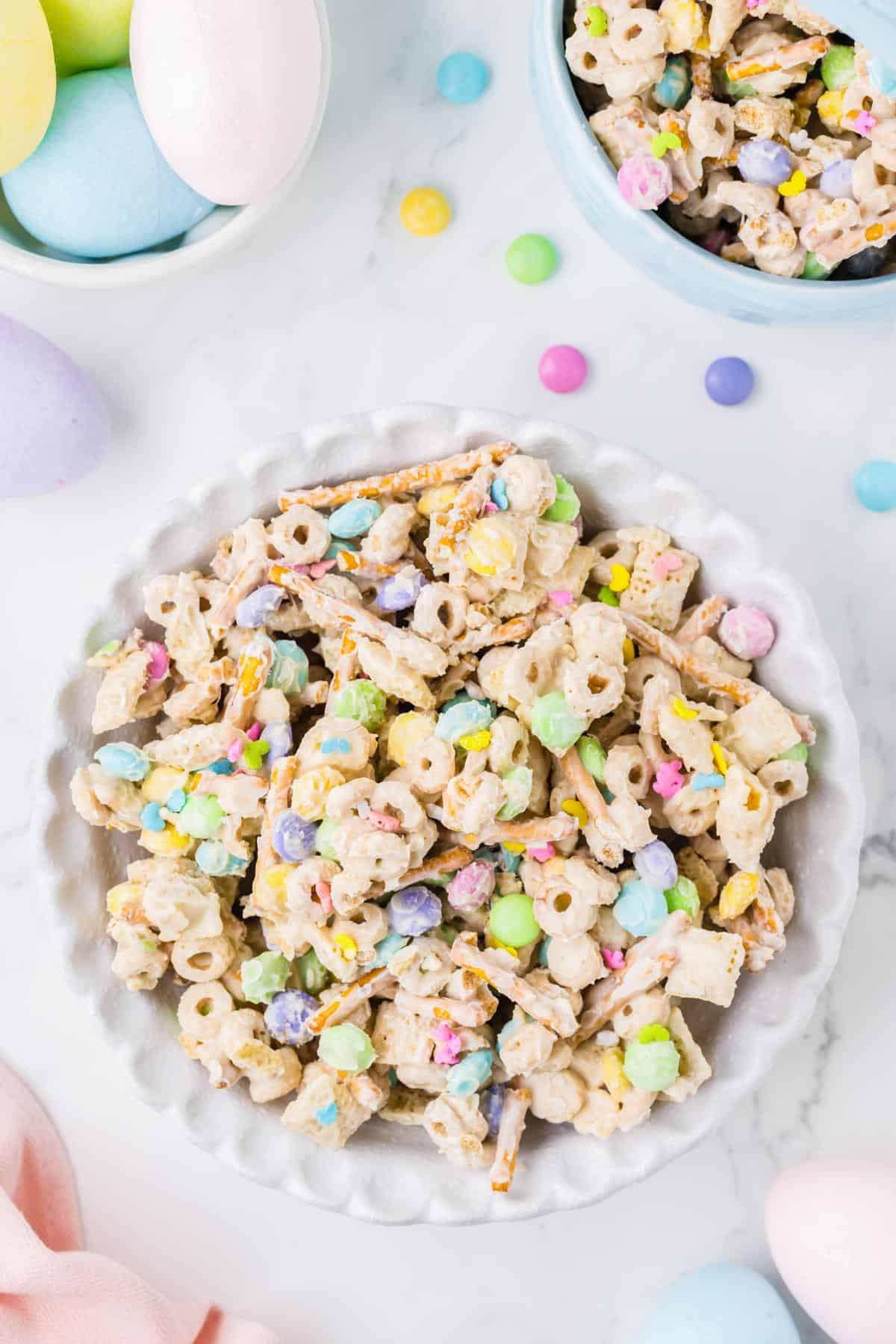 Esca per conigli 3 Una grande ciotola bianca di snack mix 'Bunny Bait' circondata da una ciotola più piccola di 'Bunny Bait' e una ciotola di uova di Pasqua