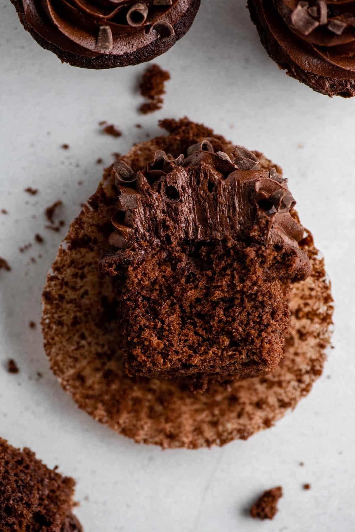 Cupcakes al cioccolato 3 Cupcake al cioccolato appoggiato di lato con un morso rimosso su sfondo grigio