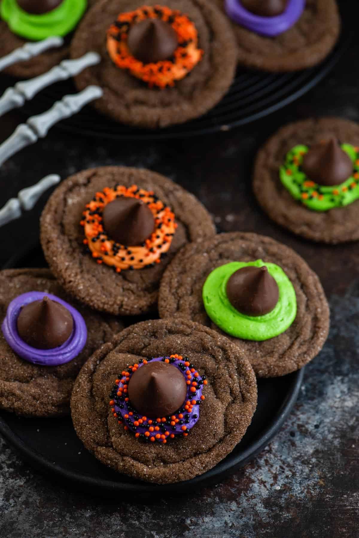 Morbidi biscotti al cioccolato sormontati da un bacio di cioccolato, glassa e zuccherini, questi Biscotti Cappello da Strega sono un dessert di Halloween facile. Vista dall'alto di biscotti a forma di cappello da strega
