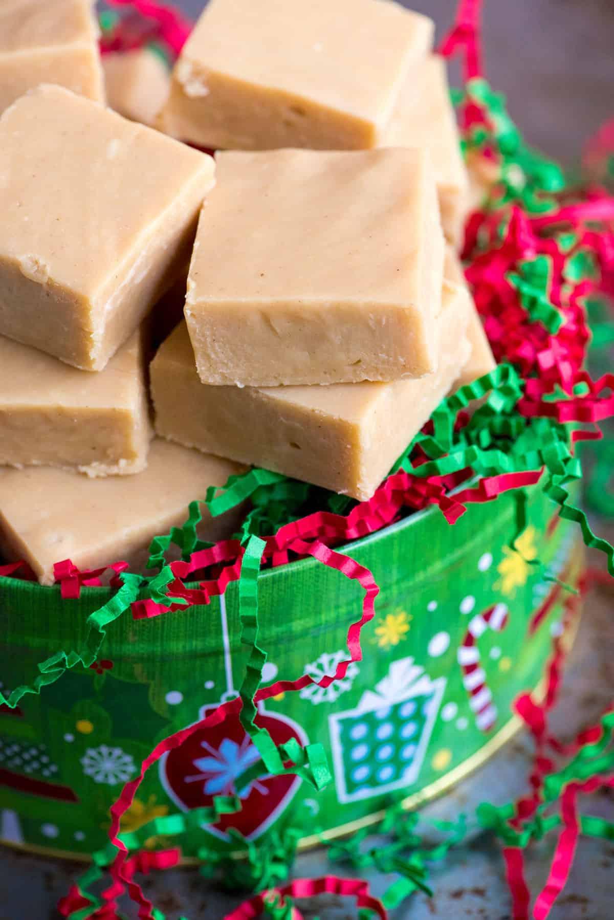 Si può congelare il fudge? 4 slices of peanut butter fudge in a christmas tin with red and green crinkle paper