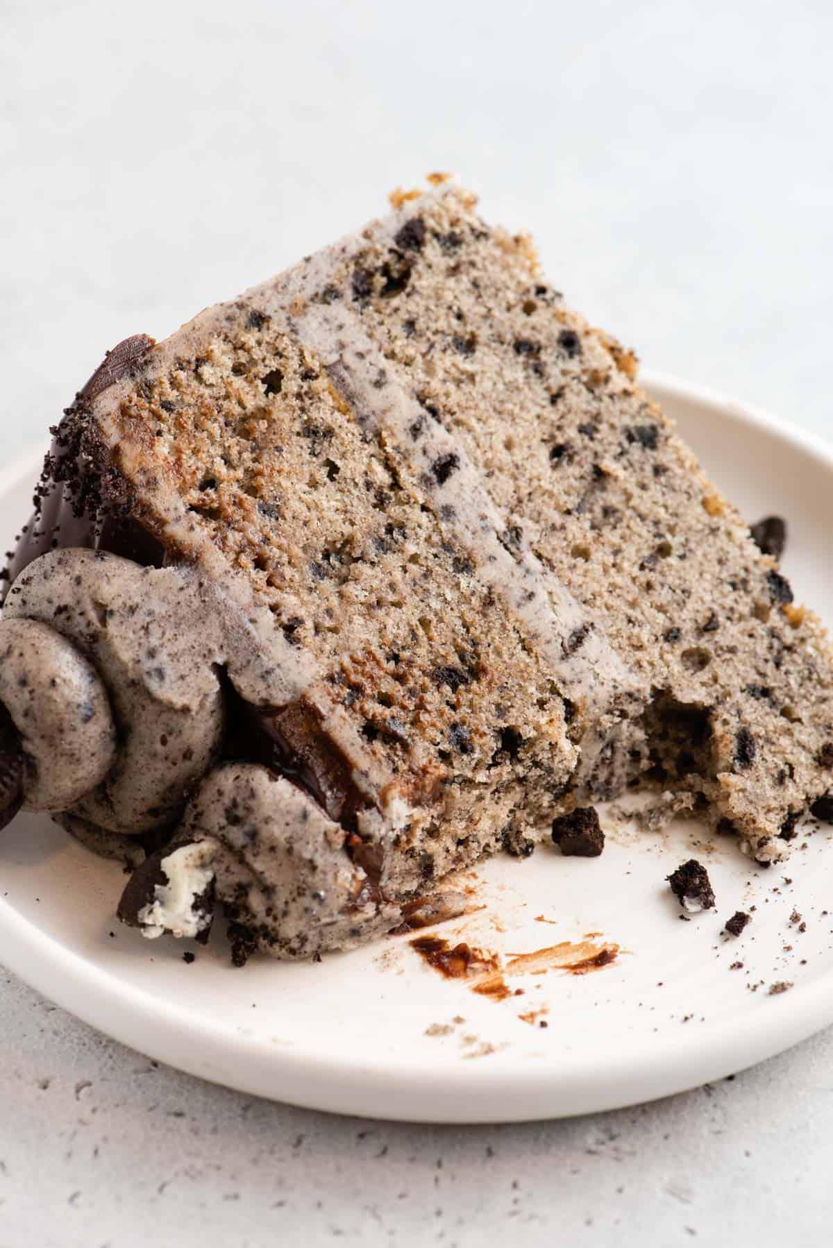 Questa torta Oreo fatta in casa è umida, ricca di sapore cookies-and-cream ed è più facile da fare di quanto tu possa pensare. Una torta a strati in stile pasticceria, fatta in casa! Fetta di torta Oreo su piatto, con parte mangiata