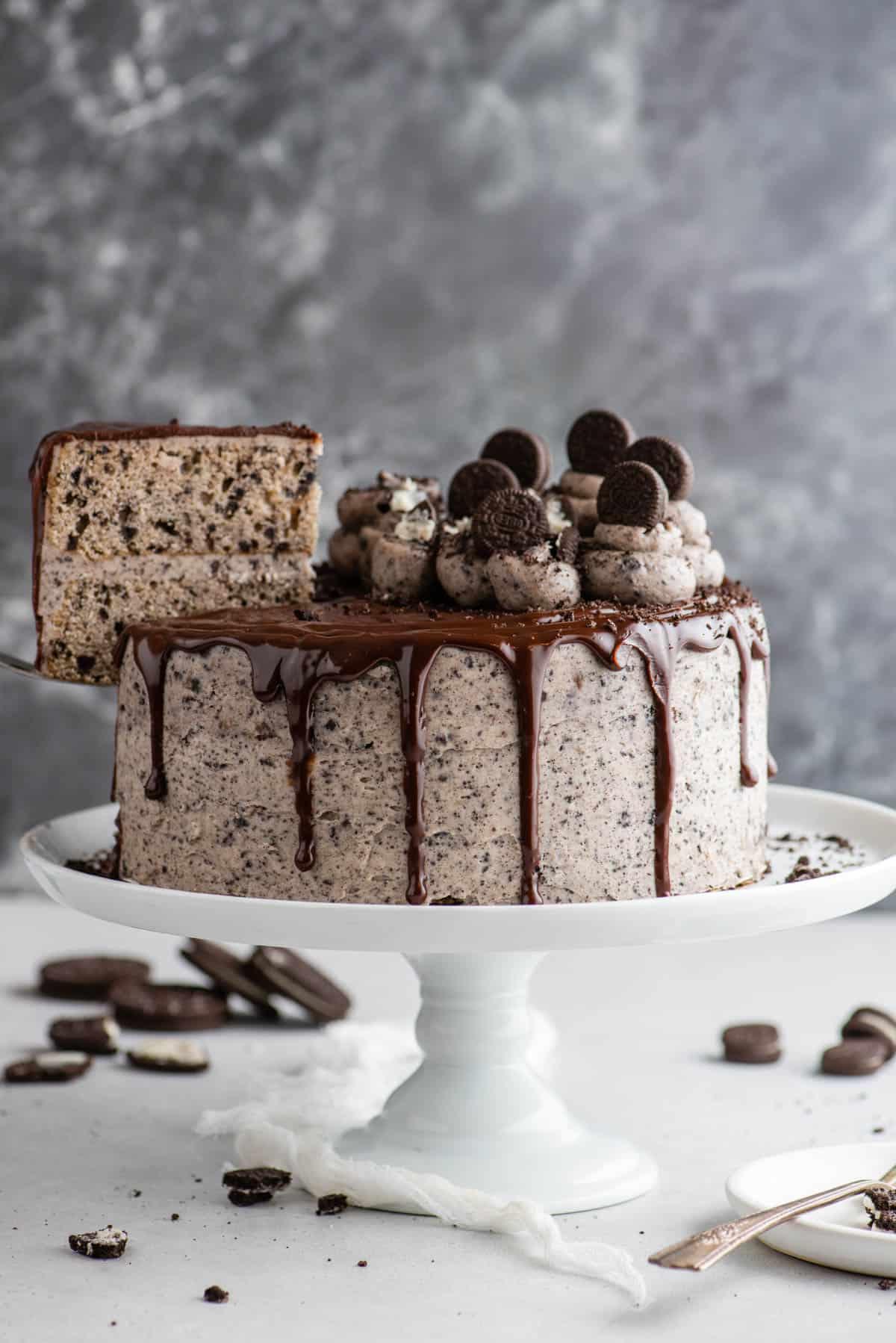 Questa torta Oreo fatta in casa è umida, ricca di sapore cookies-and-cream ed è più facile da fare di quanto tu possa pensare. Una torta a strati in stile pasticceria, fatta in casa! Torta Oreo intera su alzata per torte con fetta rimossa