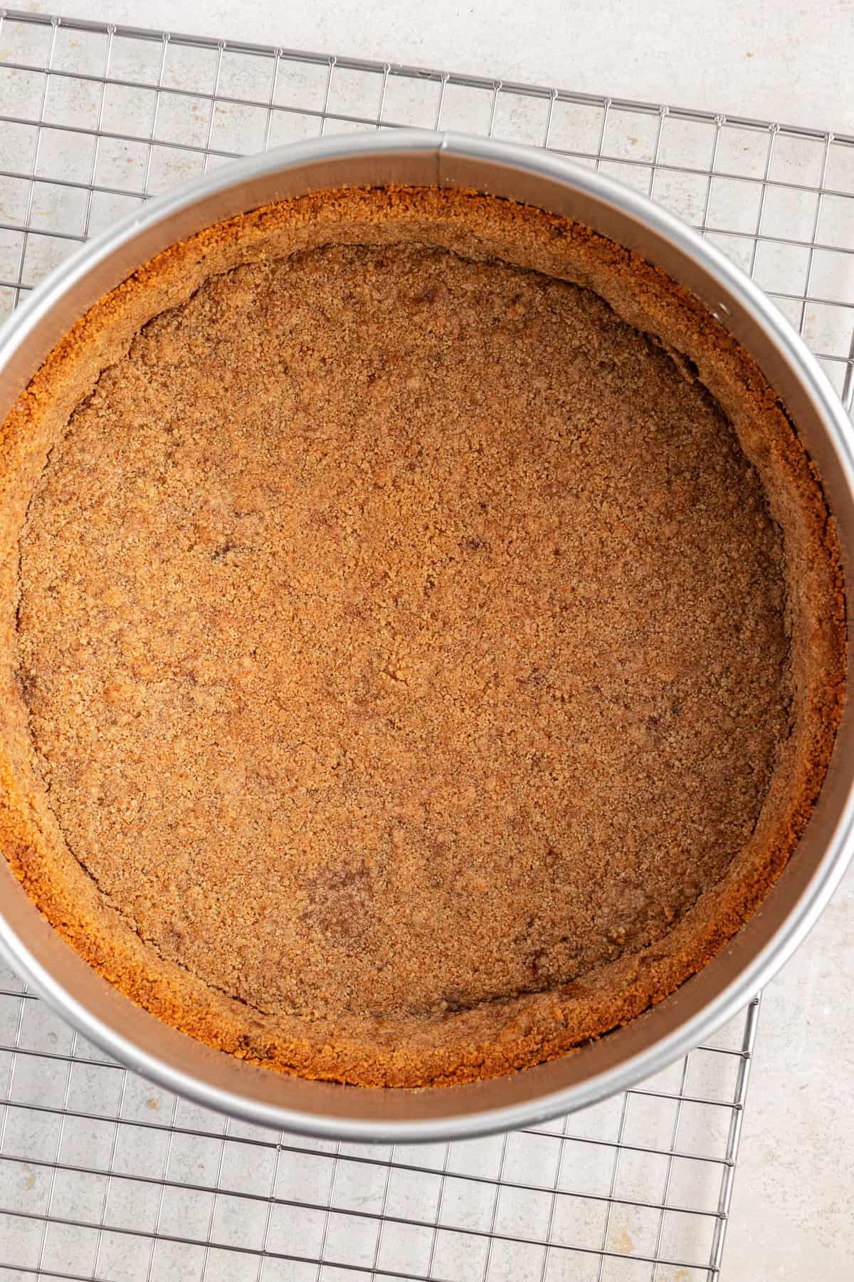 La Migliore Ricetta per Cheesecake alla Torta Pecan 7 Base di biscotti graham in una tortiera a cerniera sopra una griglia