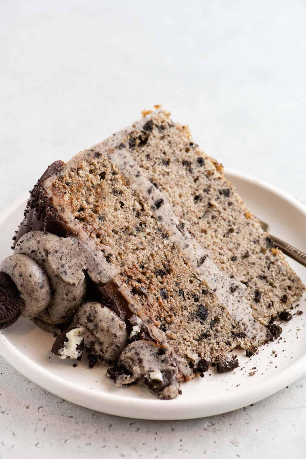 Questa torta Oreo fatta in casa è umida, ricca di sapore cookies-and-cream ed è più facile da fare di quanto tu possa pensare. Una torta a strati in stile pasticceria, fatta in casa! Fetta intera di torta Oreo su piatto