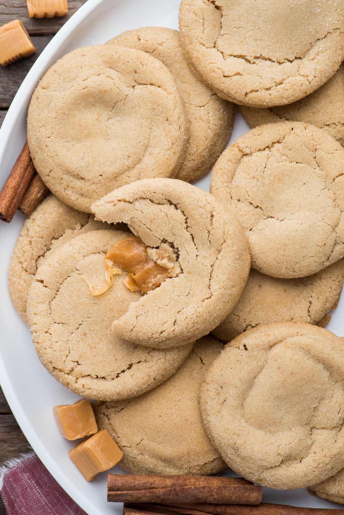 Biscotti alle Mele e al Caramello 7 apple cookies with caramel center on white round platter with caramel squares and cinnamon sticks