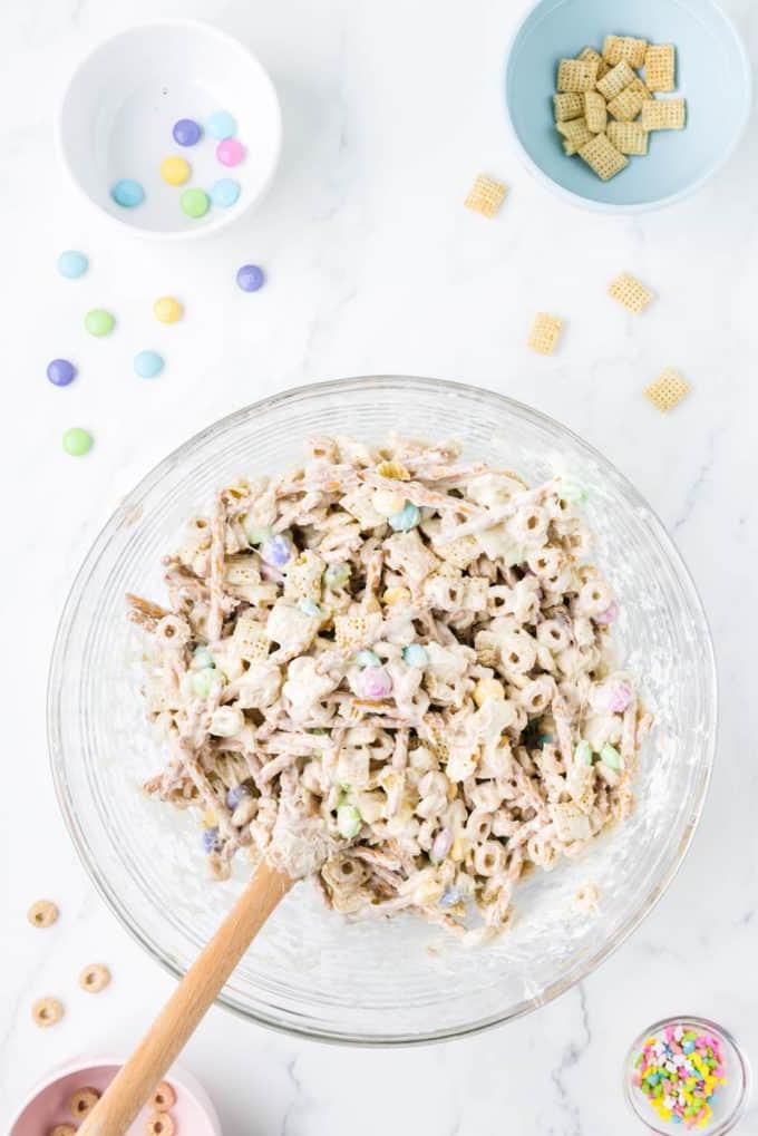 Esca per conigli 7 Snack mix 'Bunny Bait' in una ciotola di vetro trasparente circondata da una ciotola di codette, una ciotola con Cheerios, una ciotola di Chex di riso e una ciotola di M&M's