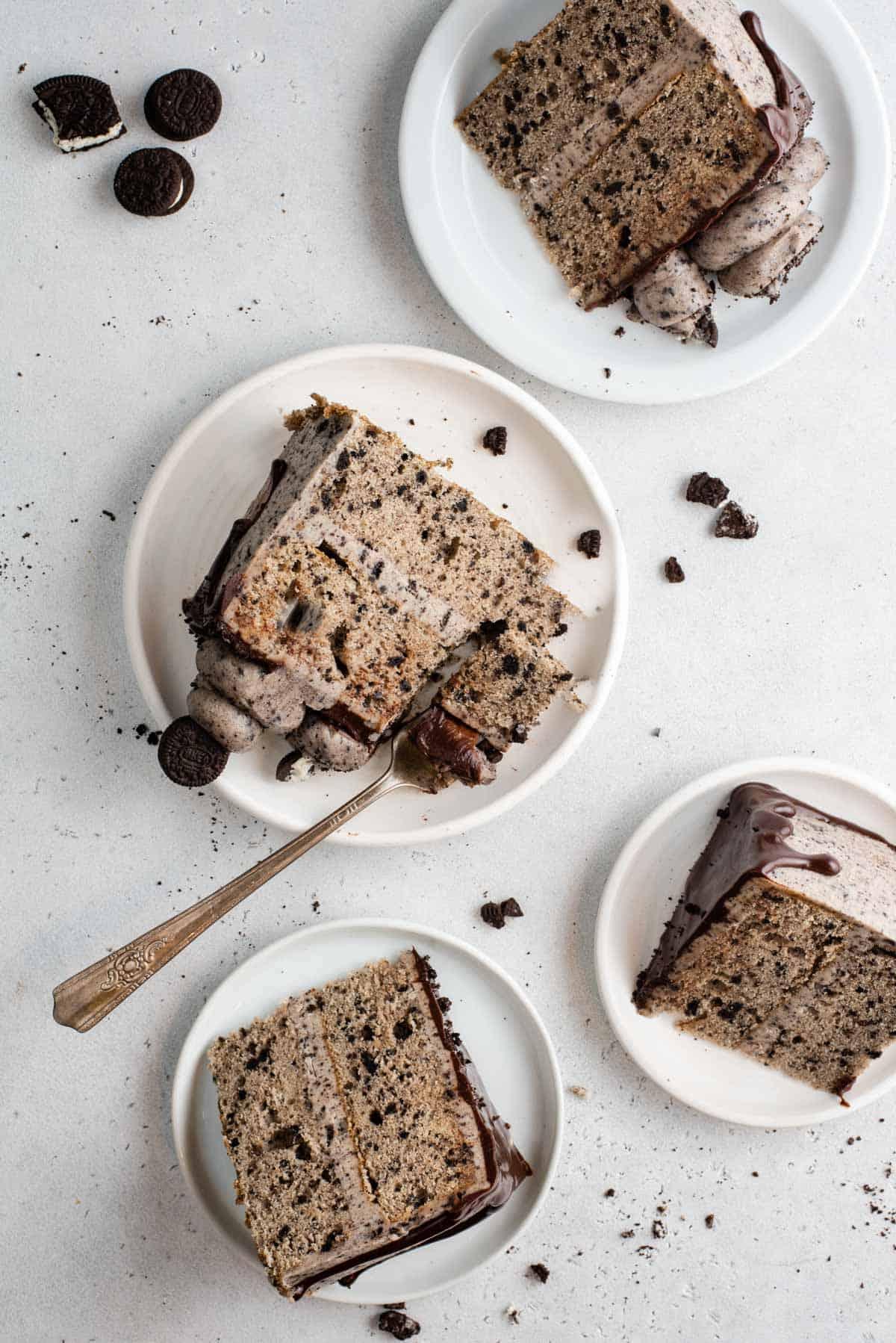 Questa torta Oreo fatta in casa è umida, ricca di sapore cookies-and-cream ed è più facile da fare di quanto tu possa pensare. Una torta a strati in stile pasticceria, fatta in casa! Vista dall'alto di 4 fette di torta Oreo su piatti