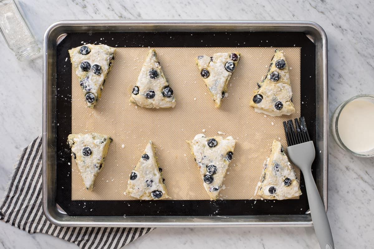 I Migliori Scones al Limone e Mirtilli 8 Scones al limone e mirtilli su una teglia con panna fresca sopra
