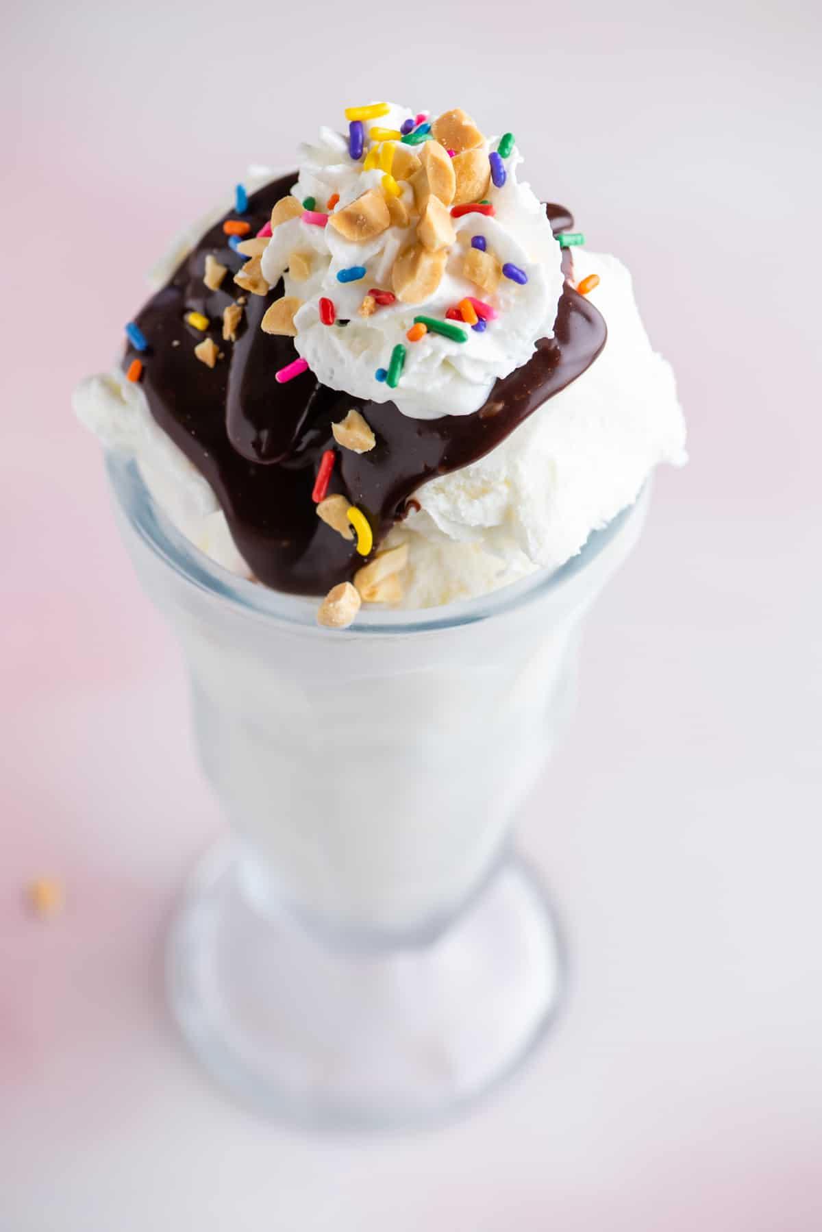 Hot Fudge Sundae 9 Un sundae al cioccolato fuso in un bicchiere alto guarnito con codette, arachidi e panna montata