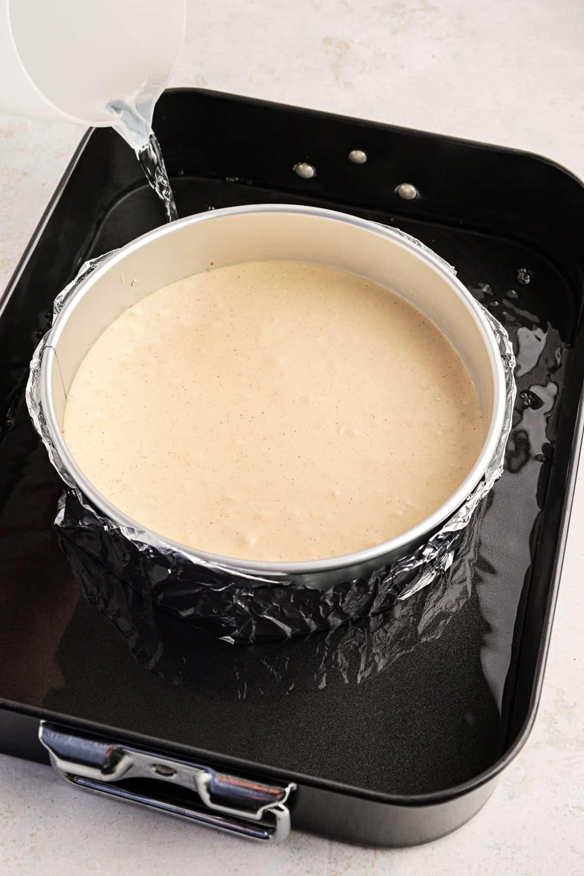 La Migliore Ricetta per Cheesecake alla Torta Pecan 9 Impasto della cheesecake in una tortiera a cerniera circondata da acqua in una teglia da forno più grande