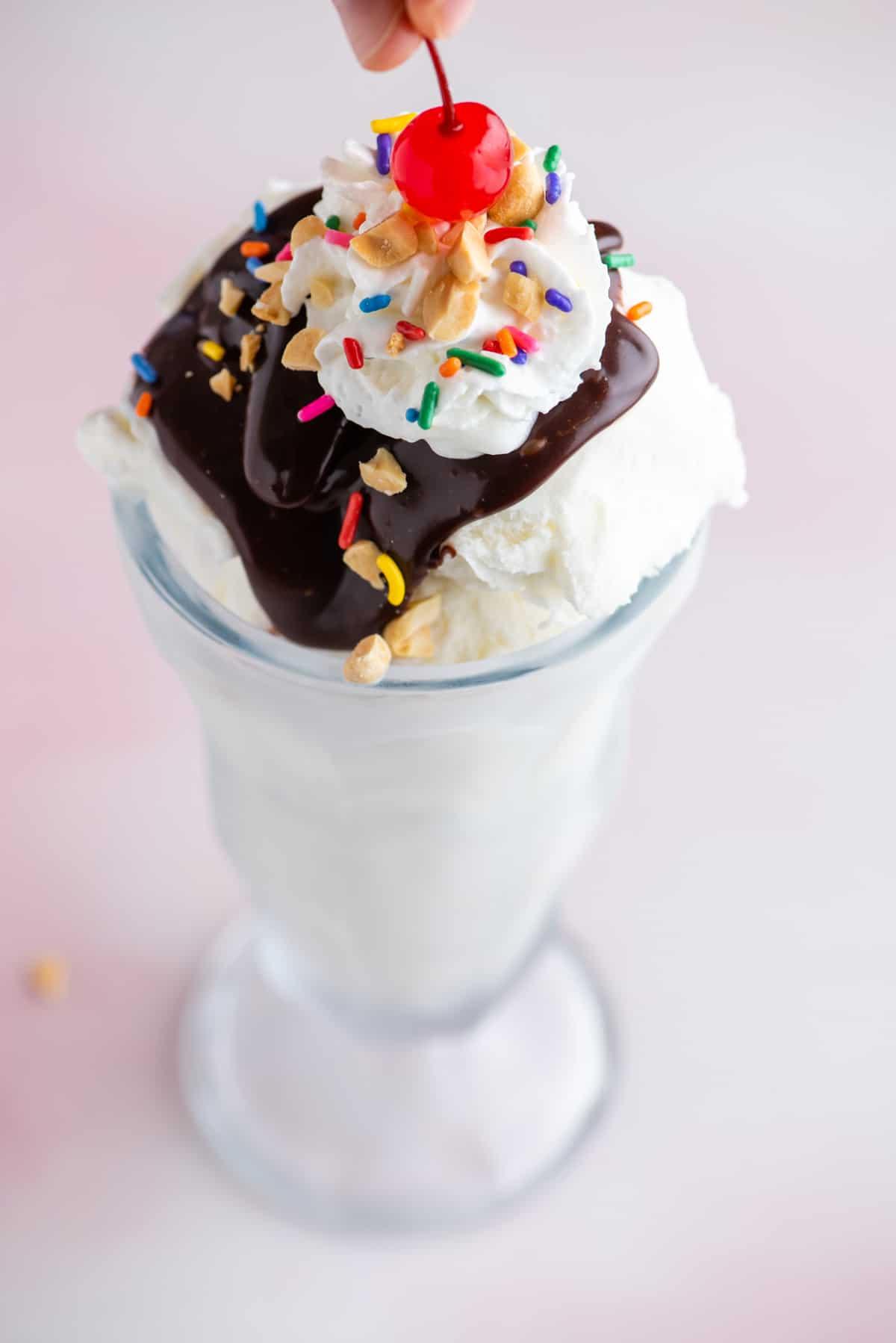 Hot Fudge Sundae 10 Un sundae al cioccolato fuso in un bicchiere alto guarnito con codette, arachidi e panna montata con una ciliegia che viene posta in cima