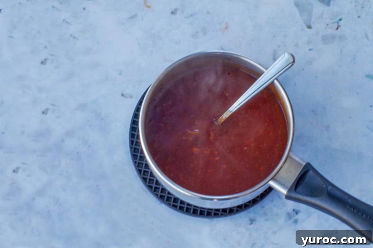 Thickened sauce in a small saucepan with a spoon. 