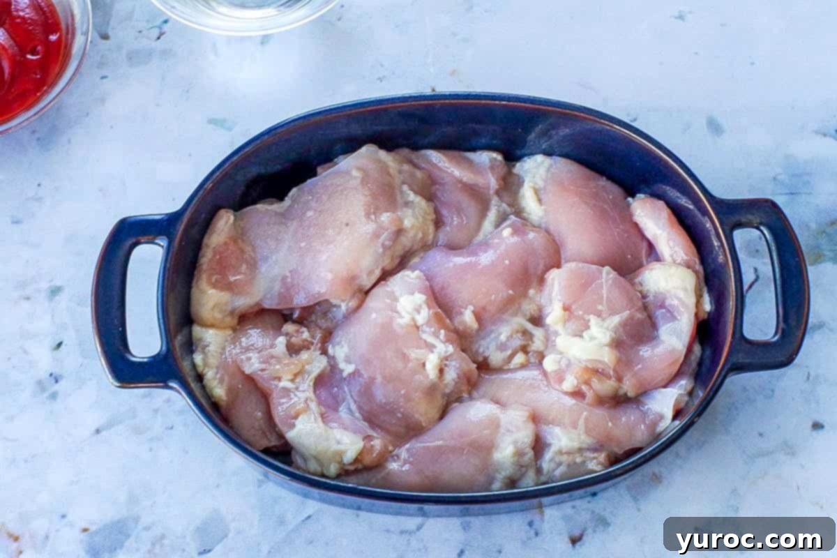 Raw chicken thighs in blue casserole dish.