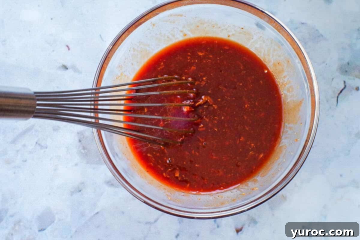 Chicken in a Hurry sauce ingredients mixed together in a glass bowl with a metal whisk.