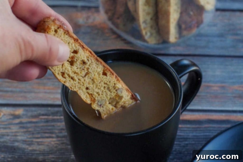 Healthy pumpkin biscotti being dipped into a warm cup of coffee, showcasing its crisp texture and perfect pairing with beverages.