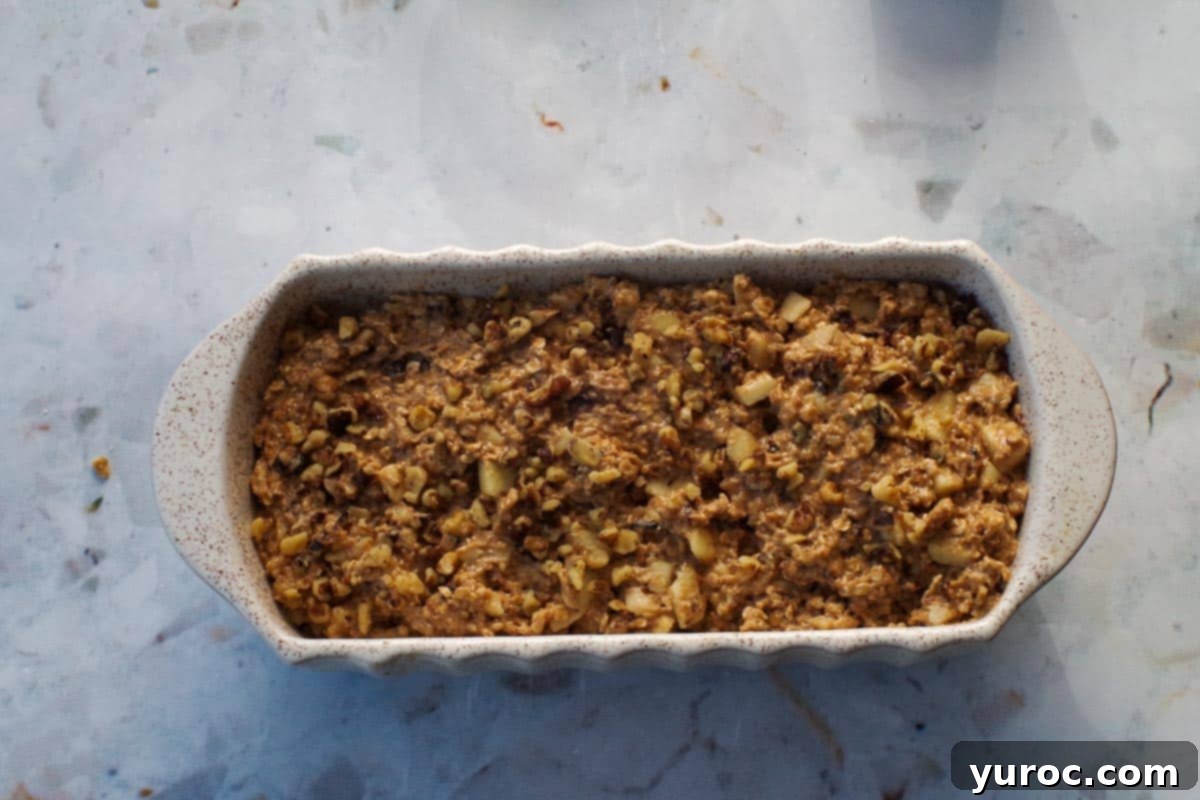 Apple walnut bread batter poured into a prepared loaf pan.