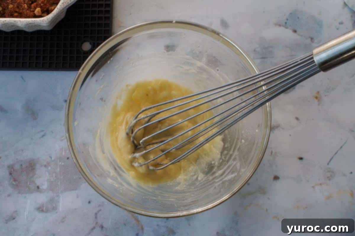 Glaze whisked together in a glass bowl with metal whisk.