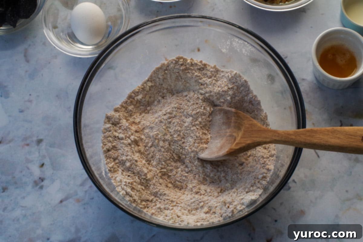 Dry ingredients in a large glass bowl with a wooden spoon.