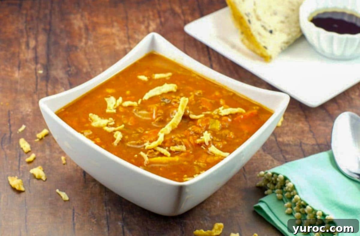 Award-winning Shredded Carrot Chowder 1 creamy carrot soup in a white bowl with bread on a plate in the background