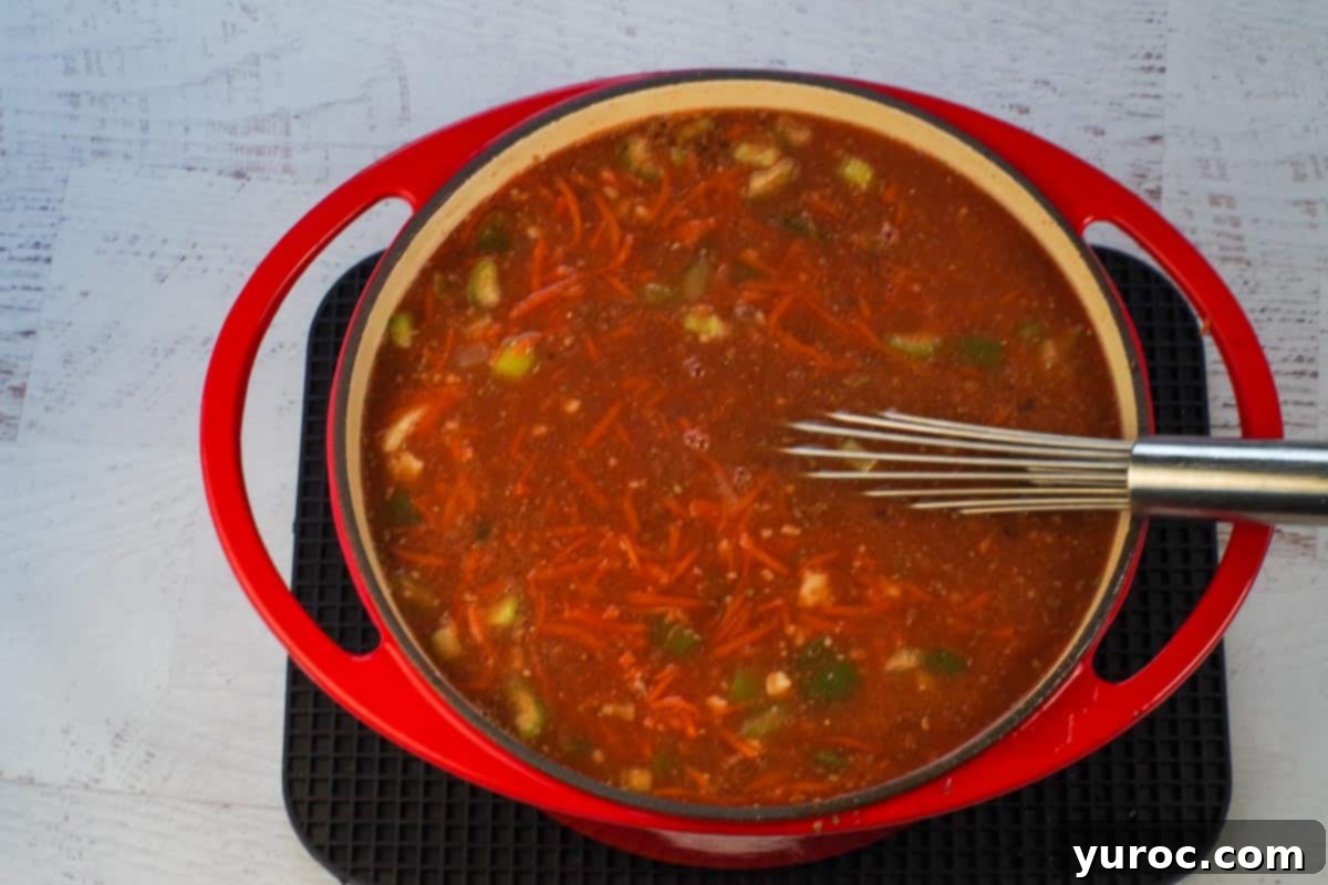 Award-winning Shredded Carrot Chowder 6 ingredients for carrot soup whisked together in orange Dutch oven, with whisk