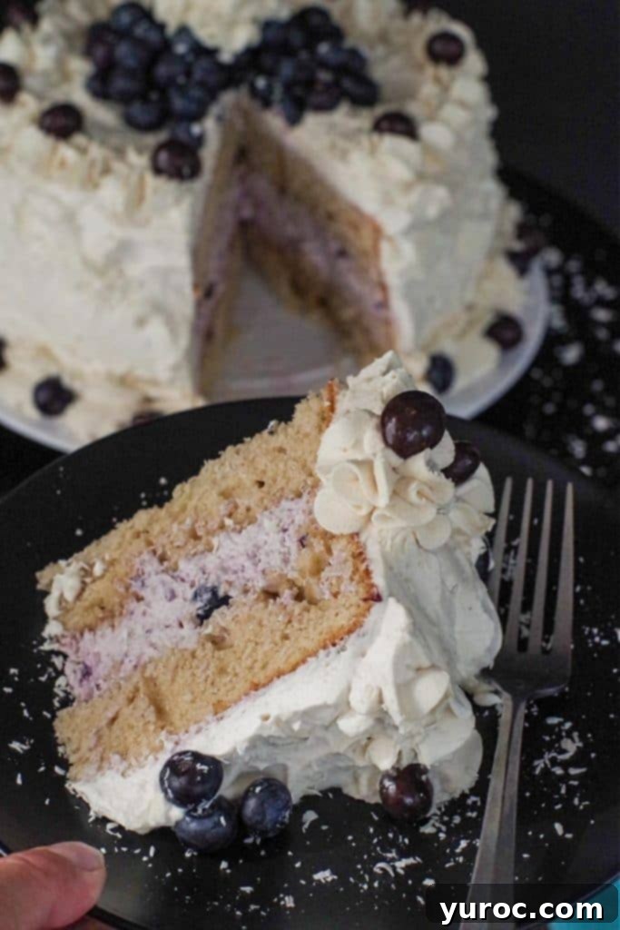 slice of coffee flavored cake on a black plate, with a fork and whole cake in background