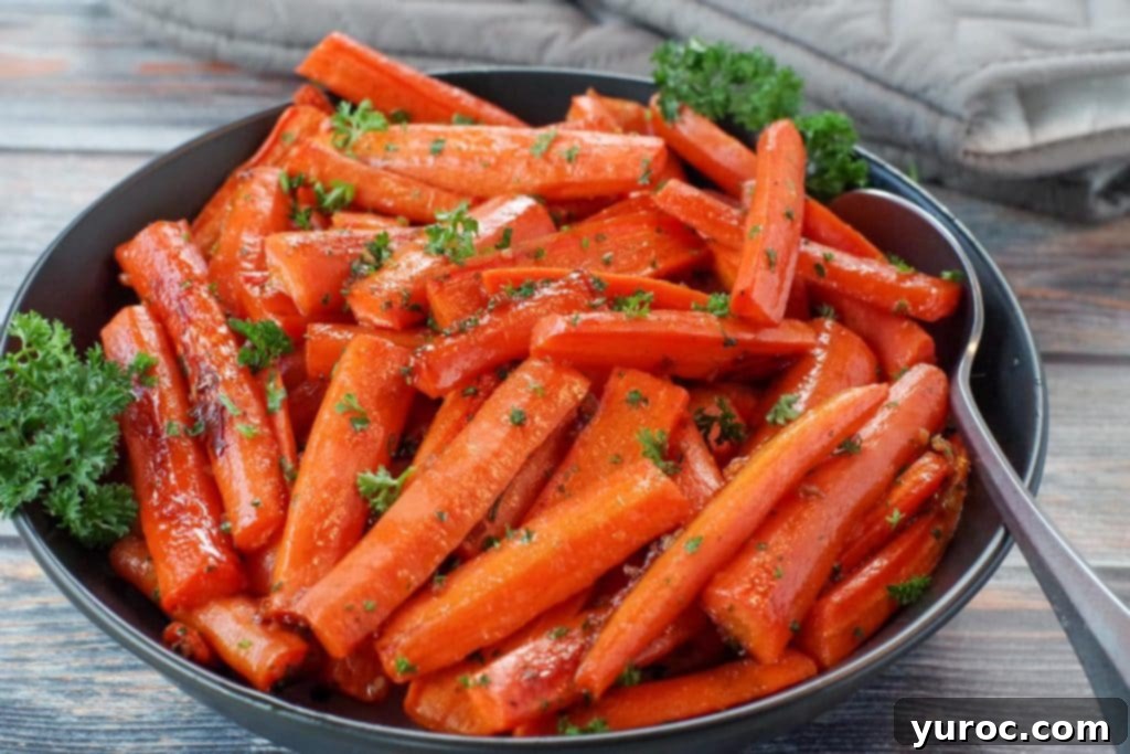 Wholesome Brown Sugar Glazed Carrots 2 Healthy roasted carrots with brown sugar in a black bowl, with a spoon and grey oven mitts in the background, showcasing their vibrant color and glaze.