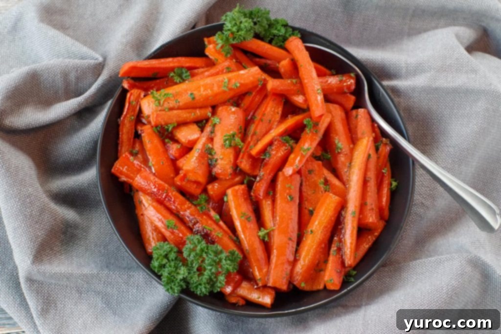 Wholesome Brown Sugar Glazed Carrots 8 Brown sugar glazed carrots in a black bowl, with a spoon, on grey linen, ready to be served and enjoyed.