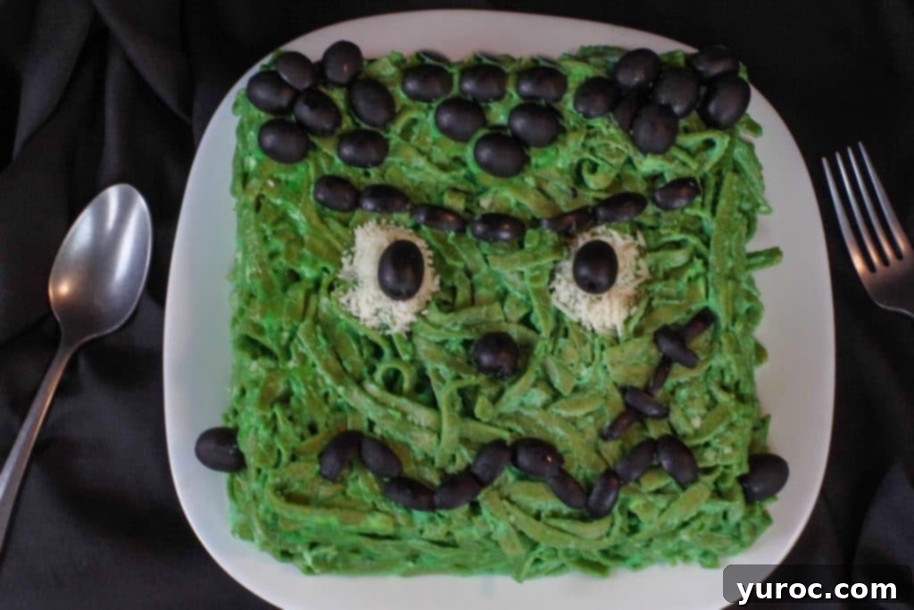 Frankenstein food (fettuccine) on a white plate with a fork and spoon on side