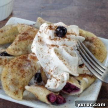 Saskatoon berry dessert pierogies on a white plate with a fork