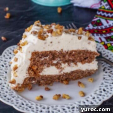 Slice Ukrainian Walnut Torte on a white plate with a whole cake in background