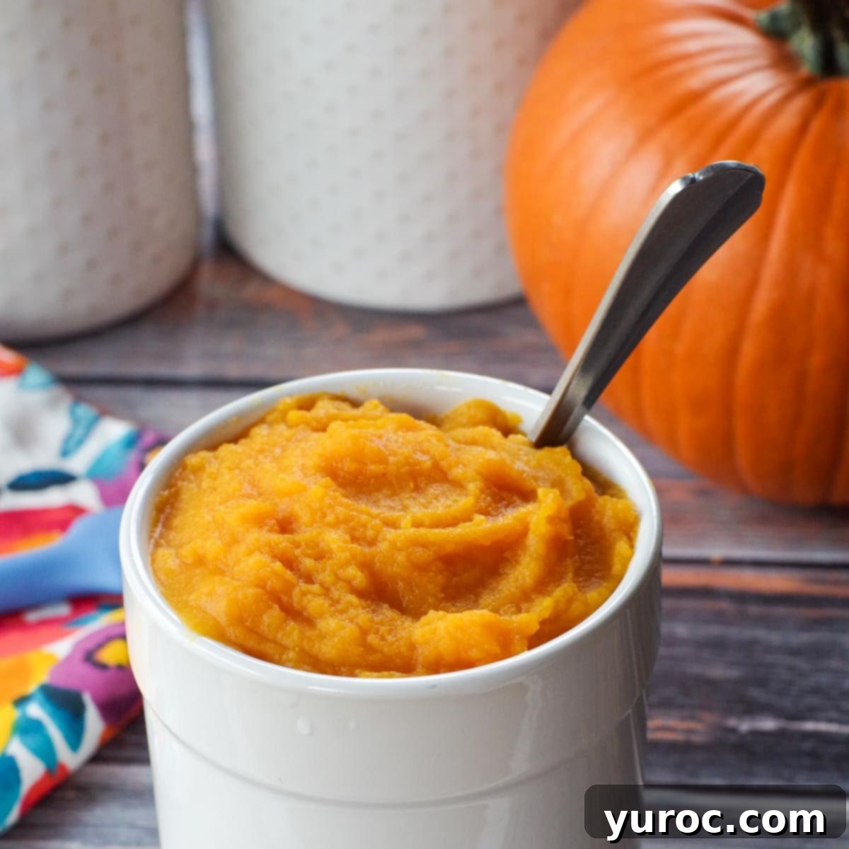 Unlock the Secrets of Whole Pumpkin Cooking and Homemade Purée 2 white canister with pumpkin puree in it, as well as spoon and whole pumpkin in background