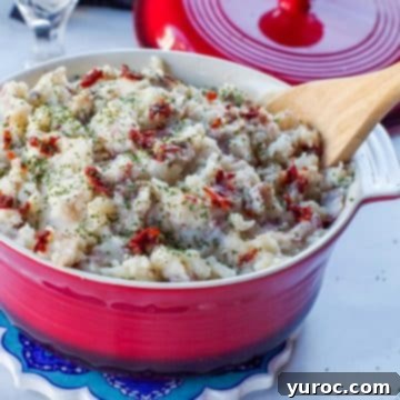 Chipotle mashed potatoes in a red serving bowl with a wooden spoon.