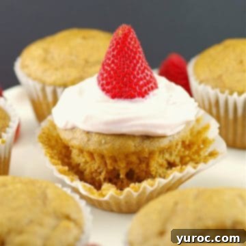 Pancake cupcake with Greek yogurt and strawberry topping, on loosened muffin liner wrapper, with other cupcake pancakes around it