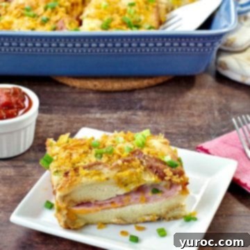 A slice of Christmas morning casserole on a white plate, on brown wooden surface, with fork on red napkin beside it, salsa in a white dish behind