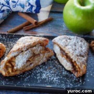 apple cinnamon scones on a black serving platter with a green apple and blue paisley patterned oven mitts in the background