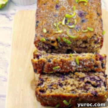 gingerbread loaf on a cutting board with blueberries and limes in background