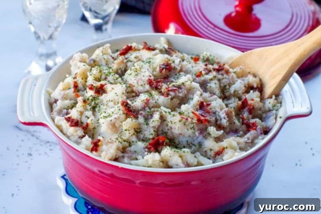 Chipotle mashed potatoes in a red serving bowl with a wooden spoon/