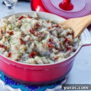 Chipotle mashed potatoes in a red serving bowl with a wooden spoon.